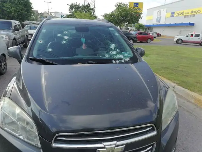 A car with multiple bullet holes in its windshield, stopped on the side of a street in Mazatlán, Sinaloa