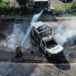 A firefighters sprays water at a smoldering truck that blocks a road in Culiacán