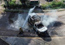 A firefighters sprays water at a smoldering truck that blocks a road in Culiacán