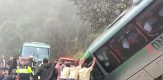 People in uniforms push on a bus that crashed on a mountainous road near Machu Picchu, Peru, while injured passengers sit and lie on the ground nearby.