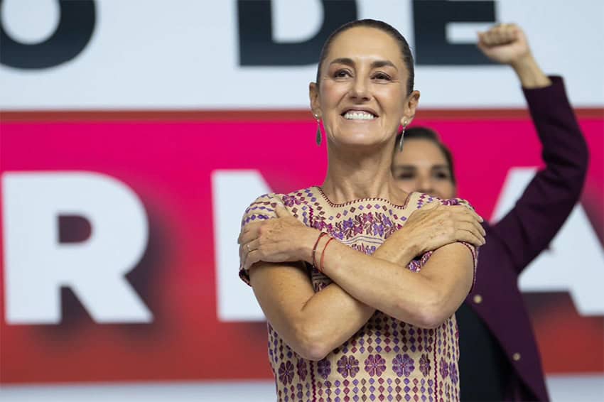 Claudia Sheinbaum crosses her arms to make a hug symbol