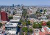 Aerial view of Colonia Americana neighborhood of Guadalajara. Skyline with multiple skyscrapers and a long avenue in the center, with a mountain range far in the background of the photo.