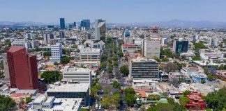 Aerial view of Colonia Americana neighborhood of Guadalajara. Skyline with multiple skyscrapers and a long avenue in the center, with a mountain range far in the background of the photo.