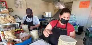 A woman tortilla vendor in Mexico weighing a large stack of tortillas