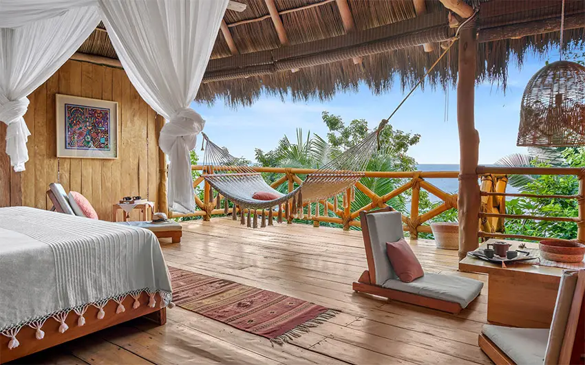 A room in Michelin Key-winning Xinalani hotel, with a palm thatch roof, hammock and ocean view.