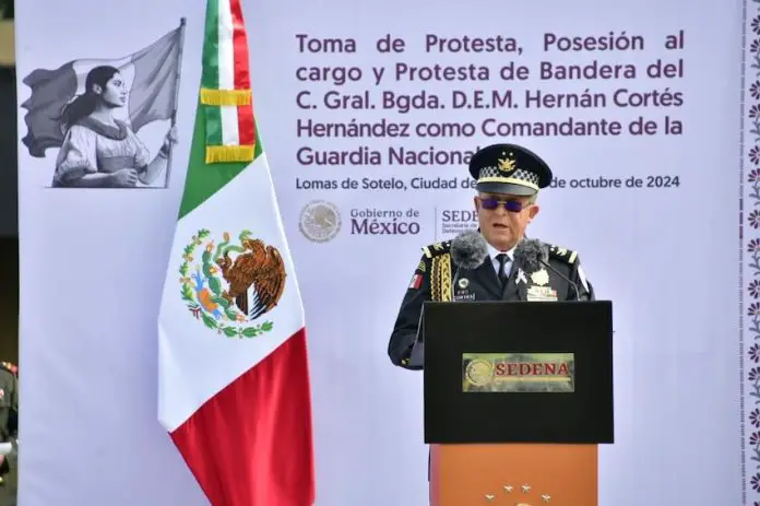 National Guard commander Hernán Cortés Hernández, dressed in military uniform, speaks at a podium next to a Mexican flag