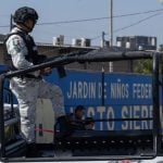National Guardsman in uniform in a truck bed on patrol through Mexican streets.