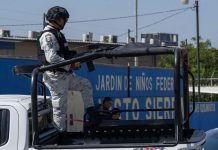 National Guardsman in uniform in a truck bed on patrol through Mexican streets.