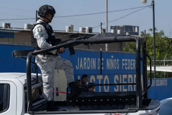 National Guardsman in uniform in a truck bed on patrol through Mexican streets.