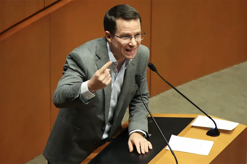 Mexican Senator Ricardo Anaya on the Mexican Senate floor, behind a podium speaking into microphones and gesturing with his index finger.