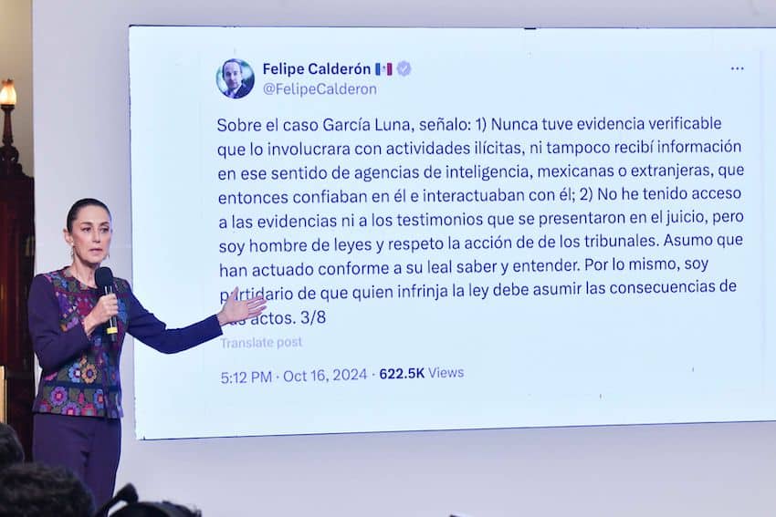 President Sheinbaum stands on a stage pointing to a projection of a tweet by Felipe Calderón