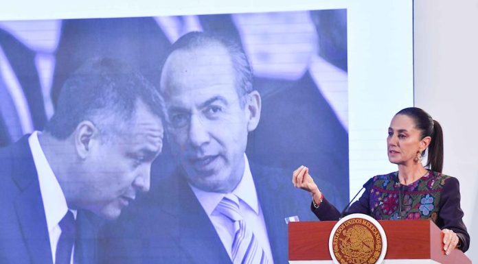 President Claudia Sheinbaum stands at a podium in front of a photo of Felipe Calderón and Genaro García Luna.