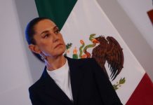 President Sheinbaum stands in front of a Mexican flag at her morning press conference