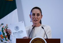 Claudia Sheinbaum at a press conference holding a copy of Mexico's Official Gazette of the Federation document