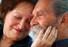 Older couple, woman holds man's face, displaying intimacy