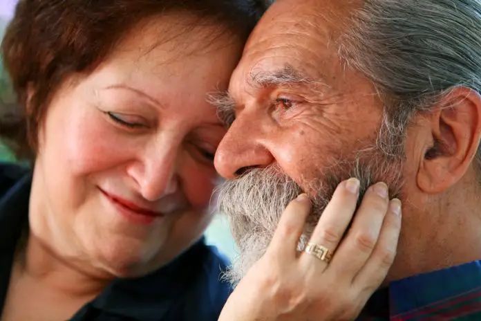 Older couple, woman holds man's face, displaying intimacy