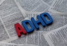 Block letters spelling out ADHD on a background of pages from a book.