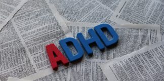 Block letters spelling out ADHD on a background of pages from a book.