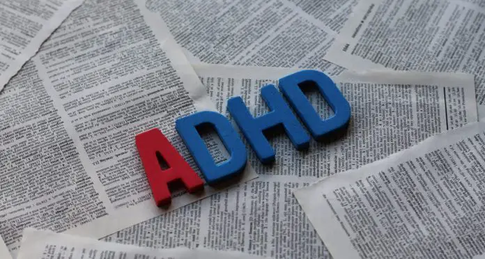 Block letters spelling out ADHD on a background of pages from a book.