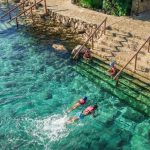 Two people swim in the turquoise waters of the Xcaret Hotel in Quintana Roo