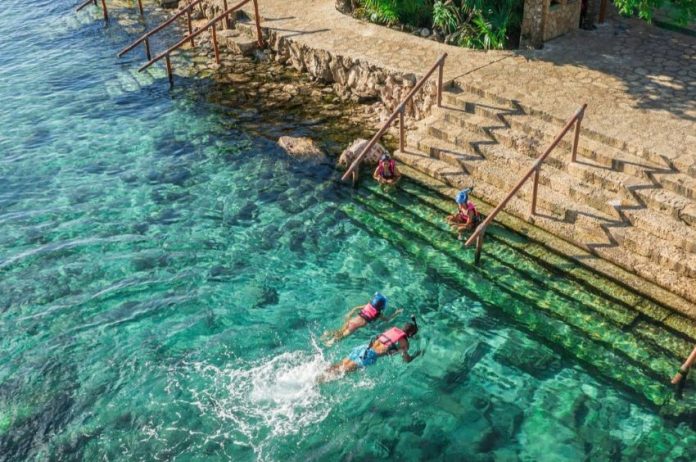 Two people swim in the turquoise waters of the Xcaret Hotel in Quintana Roo