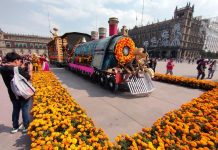 Megaofrenda in Mexico City's Zocalo square, of a parade float made to look like a steam locomotive, decorated in papel picada, Mexican marigolds and a larger-than-life figure of a Mexican revolutionary holding a gun and wearing a straw sombrero.