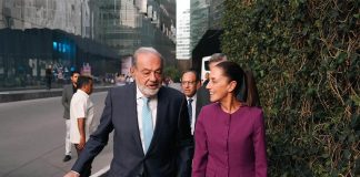 Carlos SLim and Claudia Sheinbaum walking and talking together on a sidewalk in Mexico City