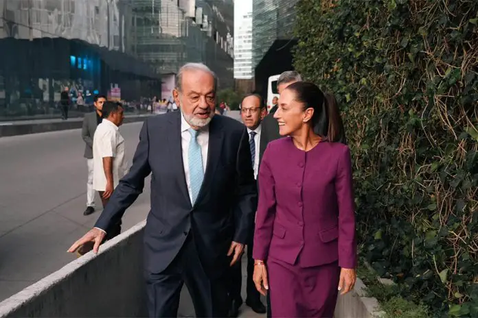 Carlos SLim and Claudia Sheinbaum walking and talking together on a sidewalk in Mexico City