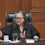 Mexican Supreme Court Chief Justice Norma Piña in session holding a gavel in the process of tapping it.