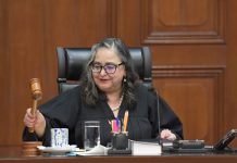 Mexican Supreme Court Chief Justice Norma Piña in session holding a gavel in the process of tapping it.