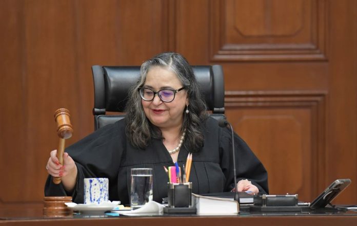 Mexican Supreme Court Chief Justice Norma Piña in session holding a gavel in the process of tapping it.