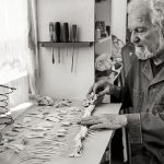 Black and white photo of artist Alan Glass laying out the skeleton of some sort of long fish-like animal in his art studio.