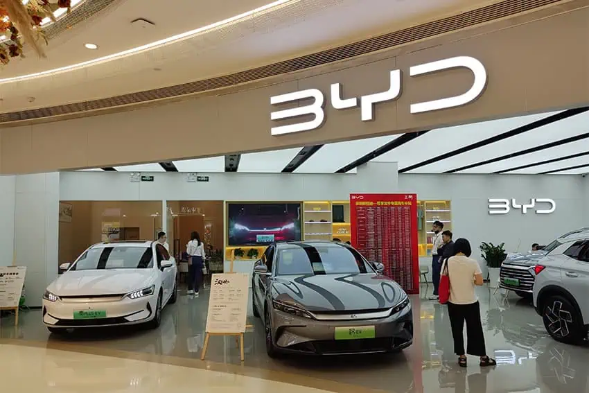 Sala de exposición de BYD con autos en exhibición y gente comprando