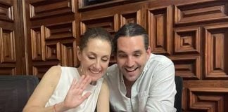 Claudia Sheinbaum and her stepson Rodrigo Ímaz Alarcón, sitting in a restaurant at a table with coffee cups and looking at something on a cell phone