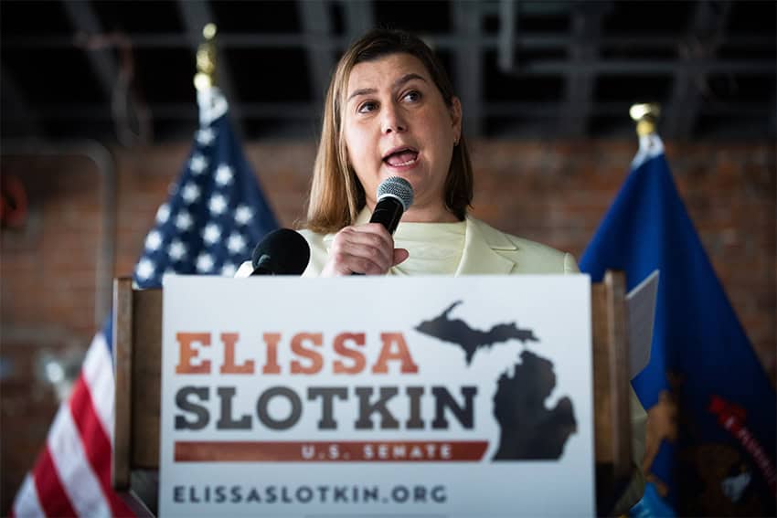 Elissa Slotkin standing a a podium with a campaign sign for the US Senate in front of it