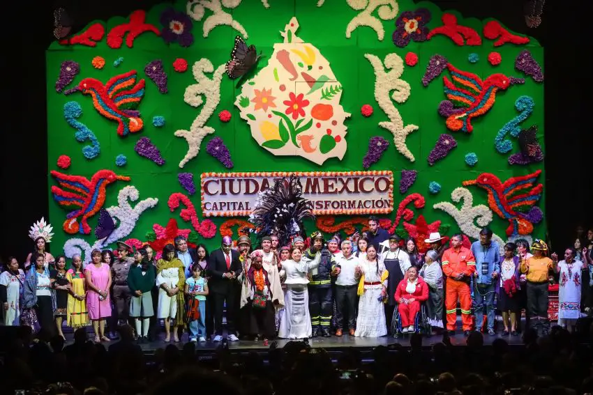 Clara Brugada stands on a crowded stage with the words "Ciudad de México" and "Transformación" on the stage behind her