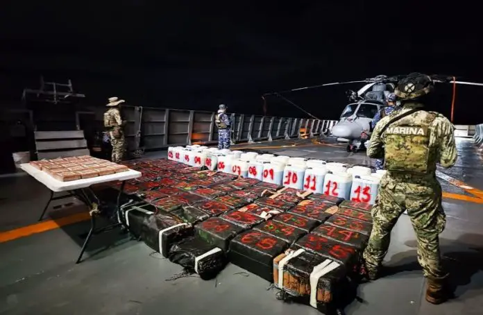 Mexican Navy officials guard the result of their maritime drug bust, with the drugs laid out for a photo