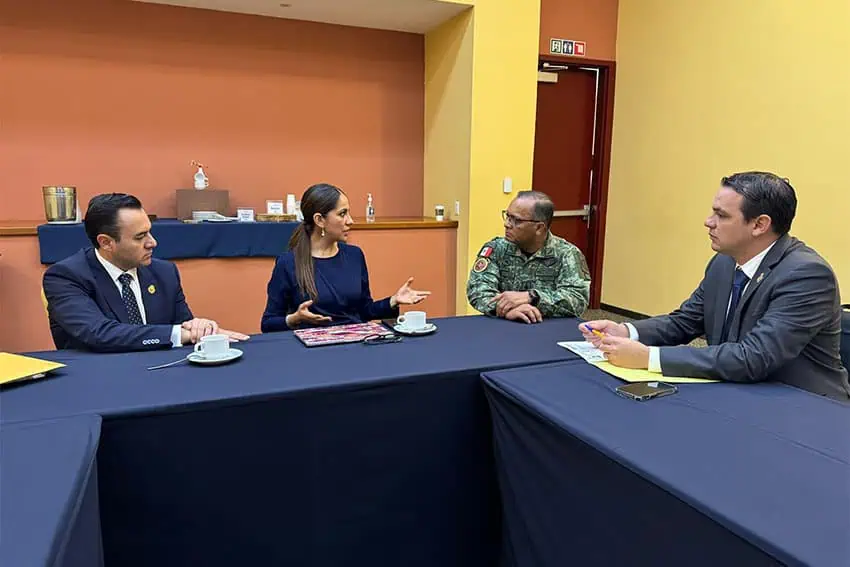 Guanajuto, México, la alcaldesa Libia García en una pequeña sala de conferencias sentados en mesas de conferencias en forma de U con dos hombres de traje y un hombre con uniforme militar