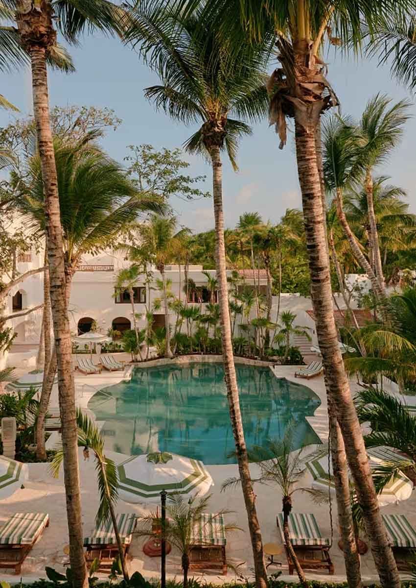 kidney shaped pool surrounded by tall palm trees at Maroma Hotel in Playa del Carmen