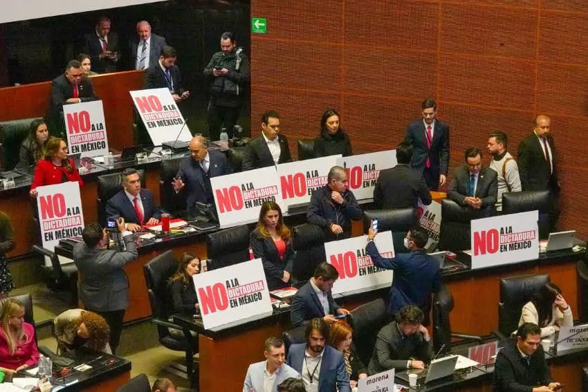 Mexican senators in session all holding signs at their desks that says in Spanish "No to dictatorship in Mexico."