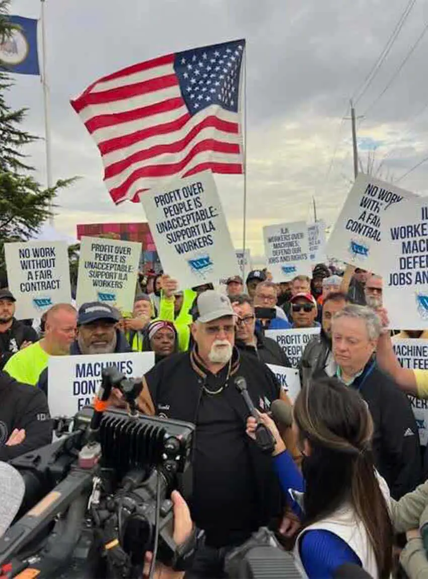 El presidente de la Asociación Internacional de Estibadores, Harold Daggett, habla con los medios mientras los miembros de la asociación están detrás de él con carteles de huelga.