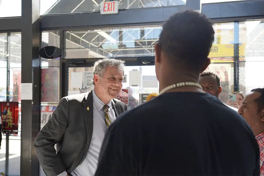 Senator Sherrod Brown in a suit talking to citizens inside a well lit building