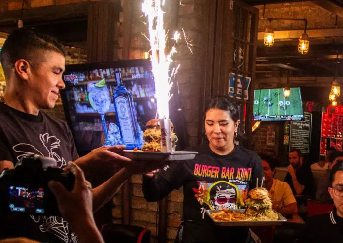 Burger Bar Joint spicy burgers being presented by staff members.