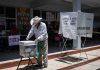 Mexican man putting a ballot into a voting box at a polling station