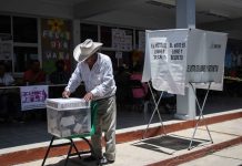Mexican man putting a ballot into a voting box at a polling station