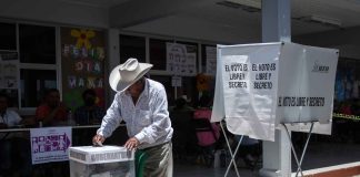 Mexican man putting a ballot into a voting box at a polling station