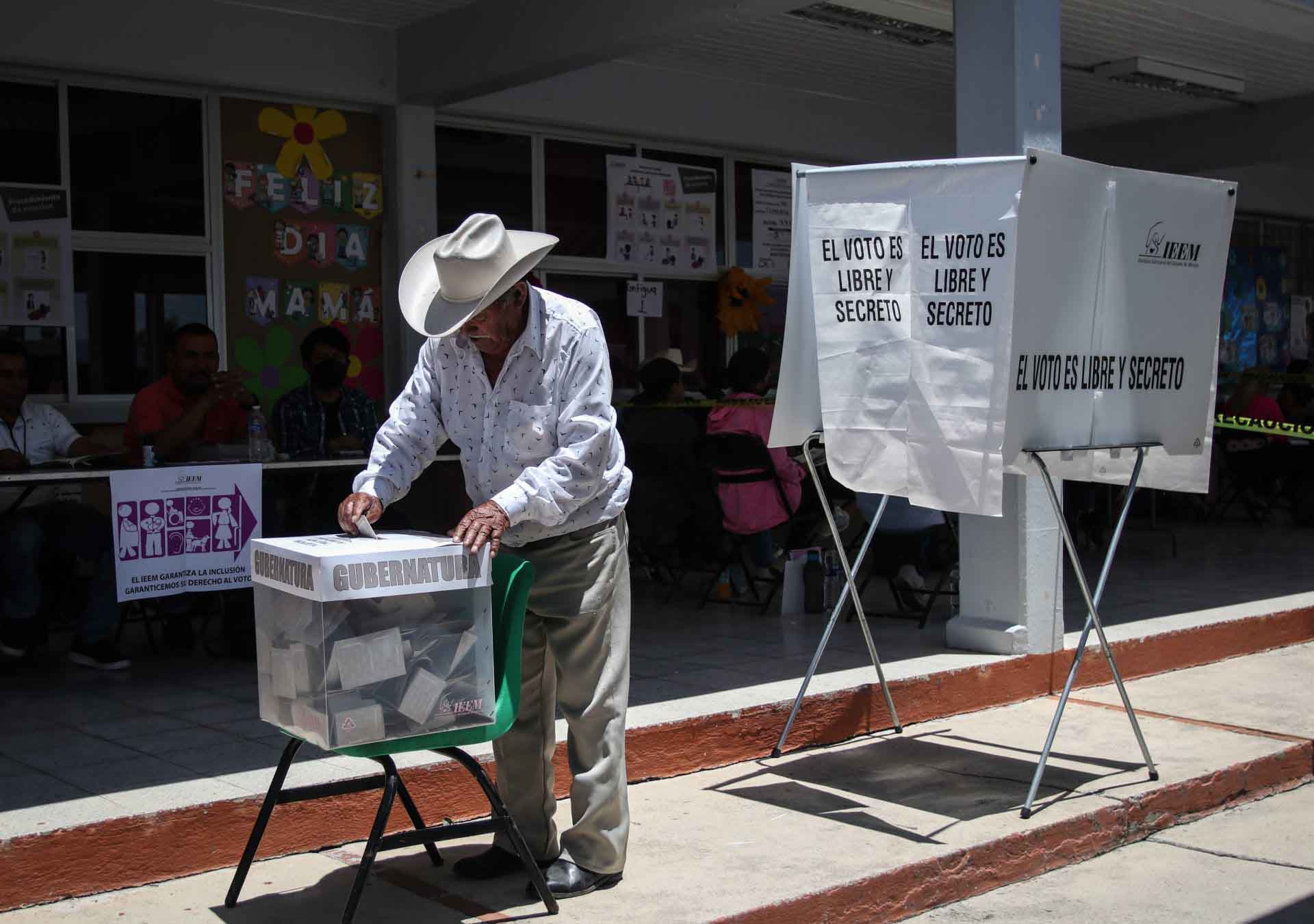 Mexican man putting a ballot into a voting box at a polling station