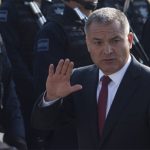 Genaro Garcia Luna in 2011 waving at the camera while Mexico's Federal Police stand at attention in rows to his right