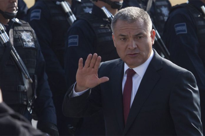 Genaro Garcia Luna in 2011 waving at the camera while Mexico's Federal Police stand at attention in rows to his right