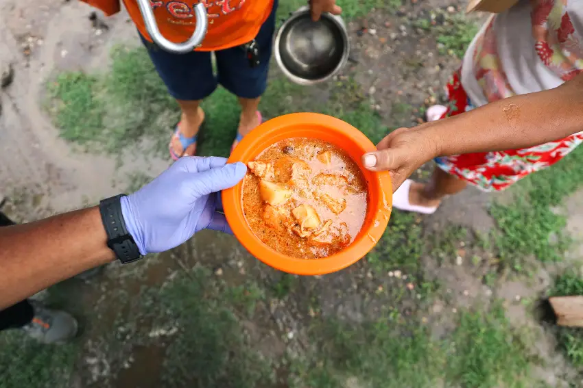 A volunteer hands a plate of food to someone